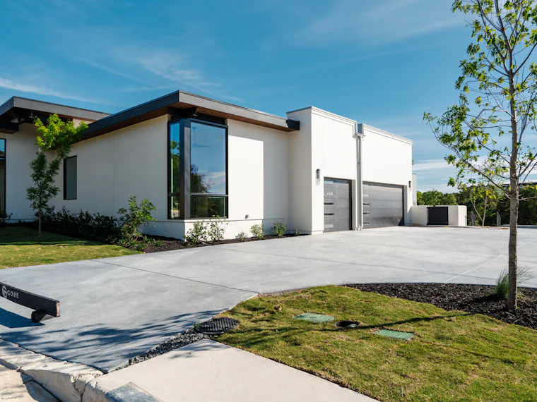 A concrete driveway running alongside a modern house