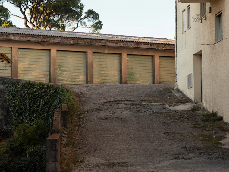 A paved driveway leading to a row of garage doors